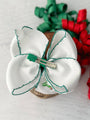 White bow hair clip with green accents on a light background