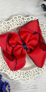 Red hair bow with blue edges on a decorative plate with flowers around.