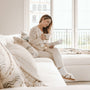 Woman reading a devotional book while sitting on a sofa near a window