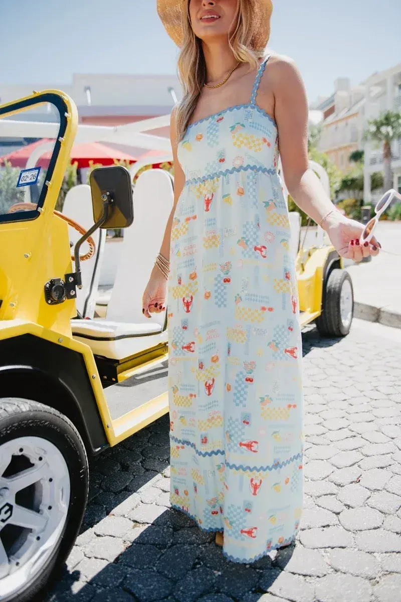 Woman in a patterned dress standing next to a yellow vehicle on a sunny day.