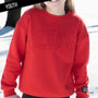 Red sweatshirt with text worn by a person, on a snowy background