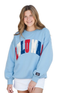 Woman wearing a light blue sweatshirt with colorful text on a white background