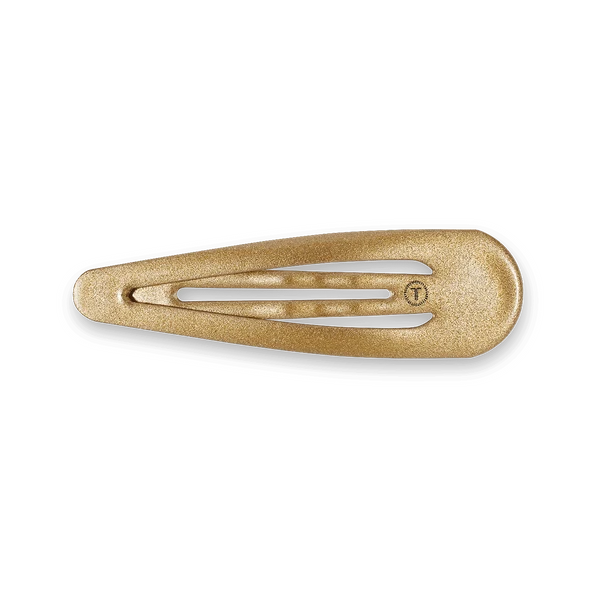A single metallic gold hair claw clip with a textured, glittery finish and a small embossed 'T' logo, shown on a clean white background.