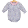 A baby long-sleeve romper with a light purple and pink floral print, featuring a contrasting pink ruffled collar and a smocked waist, displayed on a wooden hanger against a white background.