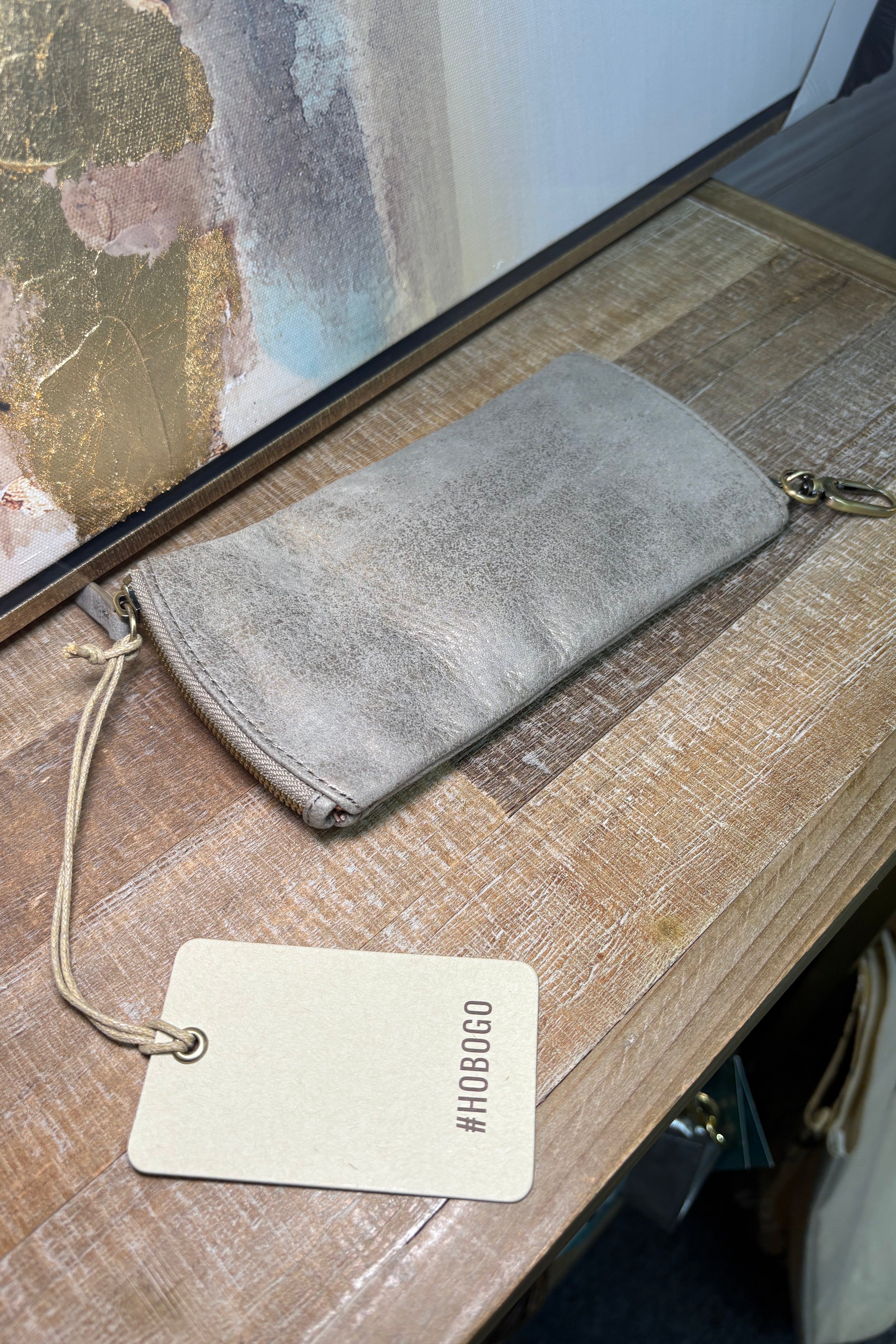 Gray suede wallet on a wooden surface with a visible brand tag.