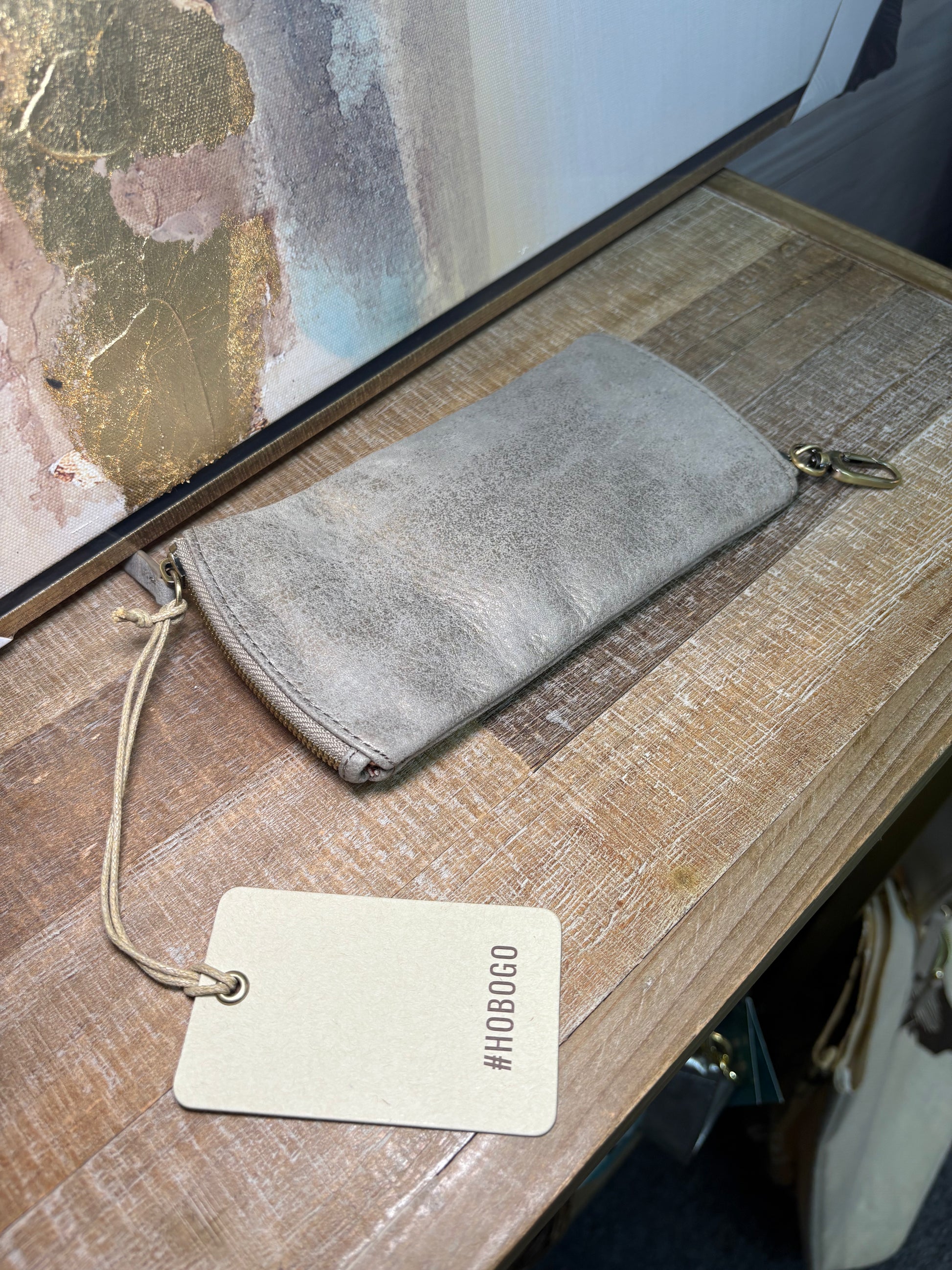 Gray suede wallet on a wooden surface with a visible brand tag.