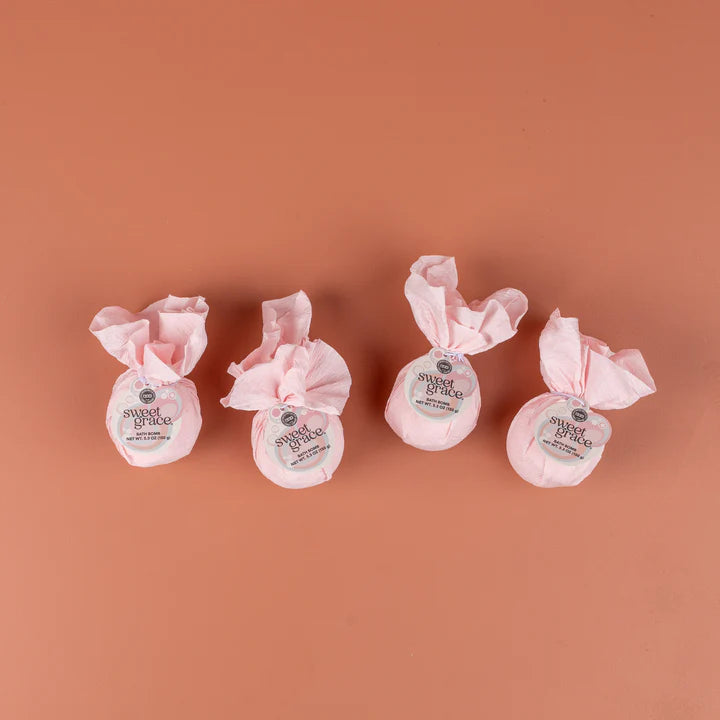 Four pink-wrapped products with labels on a brown background