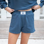 Person wearing blue sweatshirt and shorts with 'LULU MAC' label on a wooden floor.