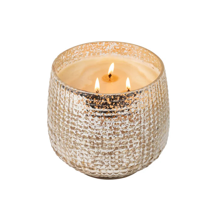 Candle in a textured metallic holder on a white background
