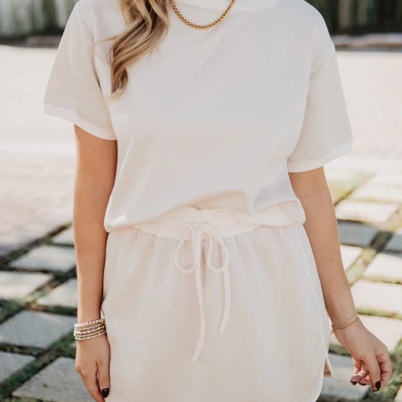 Woman wearing a white outfit with a straw hat in an outdoor setting