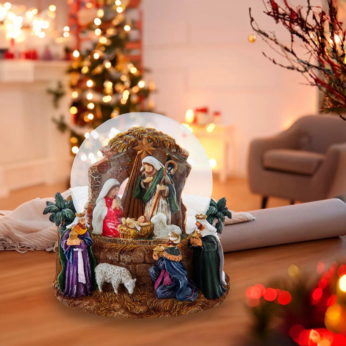 Decorative nativity scene in a snow globe with a Christmas tree in the background