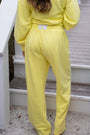 Person wearing a bright yellow outfit standing on a wooden deck.
