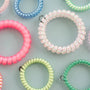 Colorful coil hair ties on a light gray background