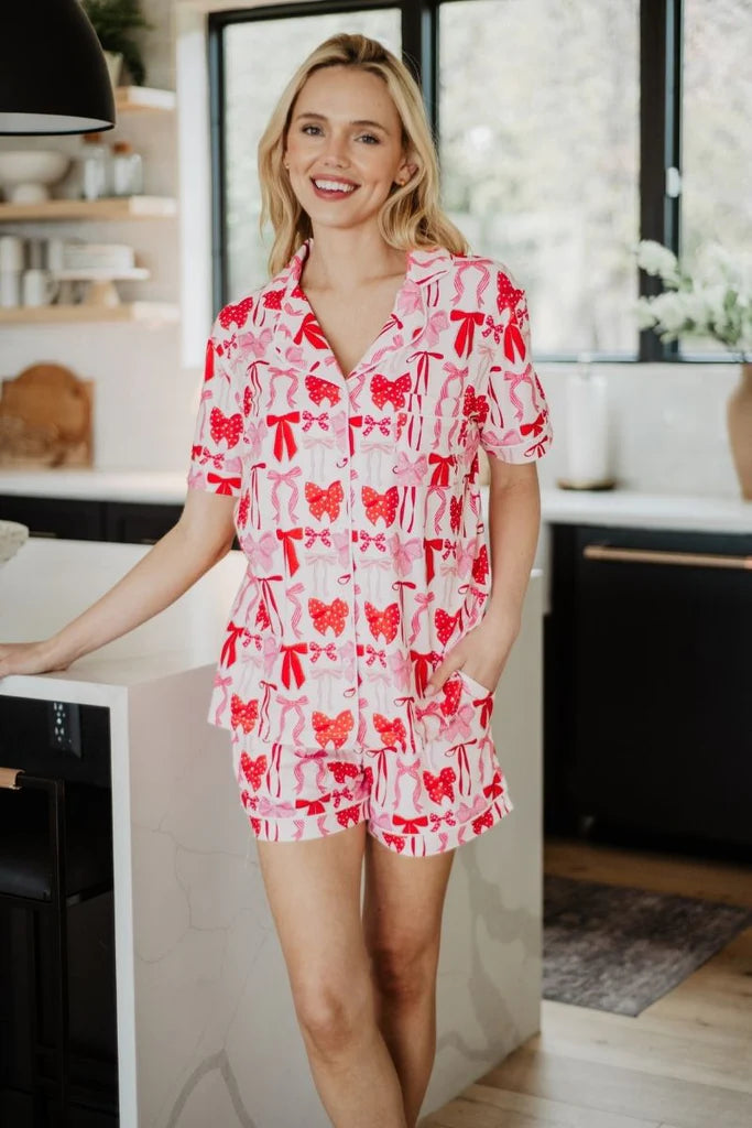 Woman wearing a red and white patterned pajama set standing in a kitchen.