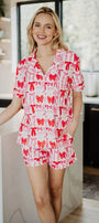 Woman wearing a red and white patterned pajama set standing in a kitchen.