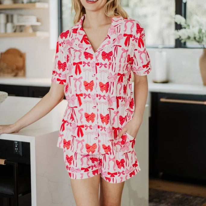 Woman wearing a red and white patterned pajama set standing in a kitchen.