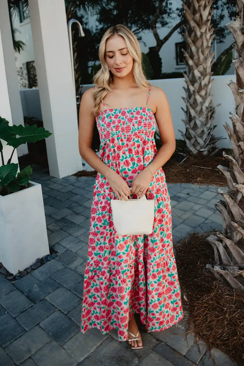 Woman in a floral dress holding a clutch in an outdoor setting