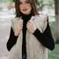 Woman wearing a beige quilted vest over a black top with a blurred outdoor background
