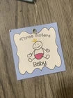 A small square baby keepsake card with a blue border and a white center, featuring a cartoon baby illustration and the words 'princess baby' on a wooden surface.