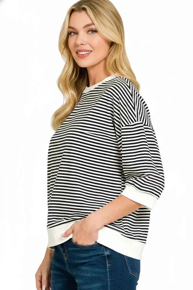 Woman wearing a black and white striped sweater with a plain background