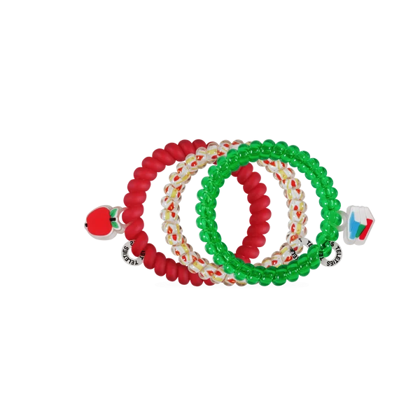 Three beaded stretch bracelets stacked together on a white background: one solid red, one green, and one white with red and green accents. Each bracelet has a small decorative charm at the end.