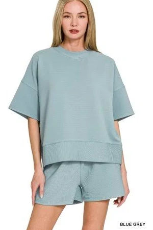 Woman wearing a light blue-grey outfit on a white background