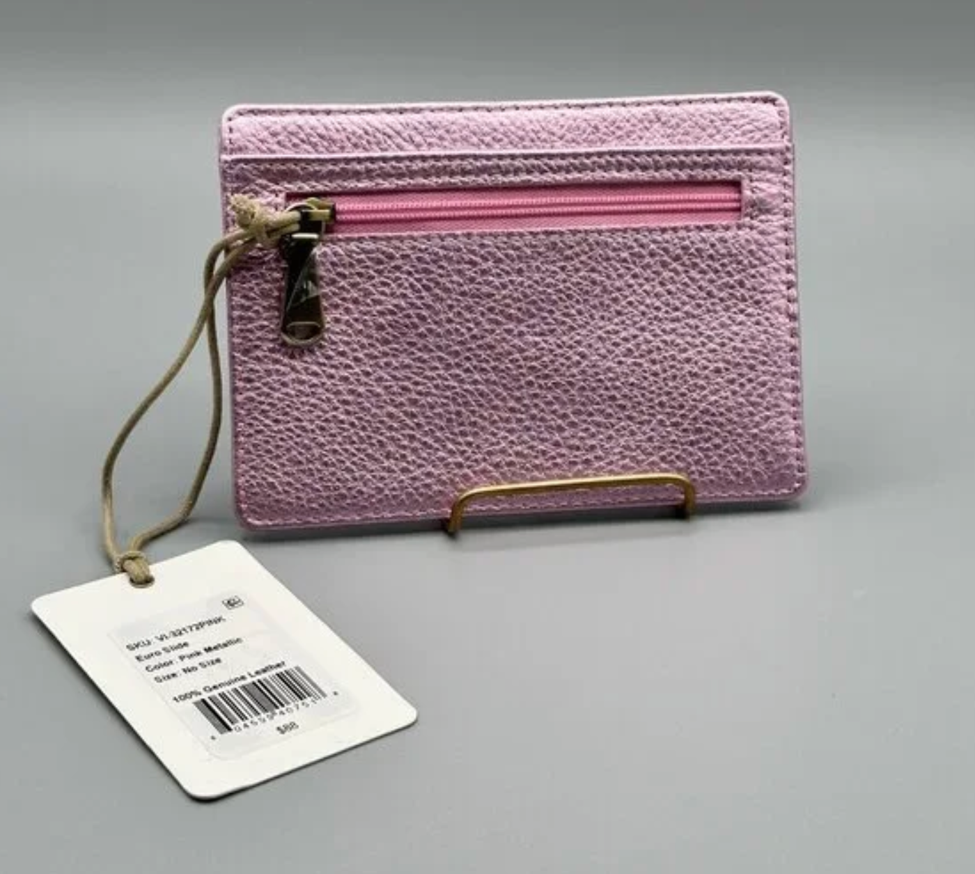 Pink textured wallet with a strap and tag on a gray background