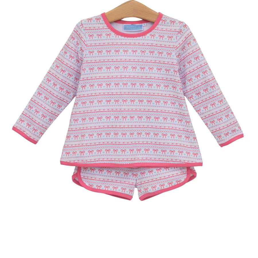 A two-piece children's pajama set consisting of a long-sleeve top and matching shorts, featuring a pink and white Nordic fair isle pattern with reindeer motifs, displayed on a wooden hanger against a white background.