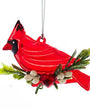 A red cardinal bird Christmas ornament with green pine branches, white berries, and a hanging loop on a white background.