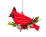 A red cardinal bird Christmas ornament with green pine branches, white berries, and a hanging loop on a white background.