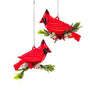Two red cardinal bird ornaments hanging from silver strings, each perched on a small green branch with white berries, shown on a plain white background.