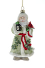 A vintage-style Santa Claus hanging ornament featuring a white-trimmed green robe, red sash, lantern, holly, and a red cardinal, shown against a plain white background.