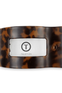 A Teleties brand tortoiseshell hair clip, featuring a classic brown and black mottled pattern with a central silver-toned metal plate displaying the black Teleties logo and a small circular detail on the right.