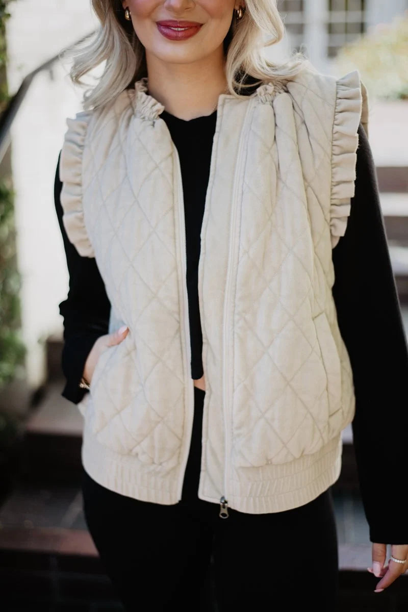 Woman wearing a cream quilted vest with a blurred outdoor background