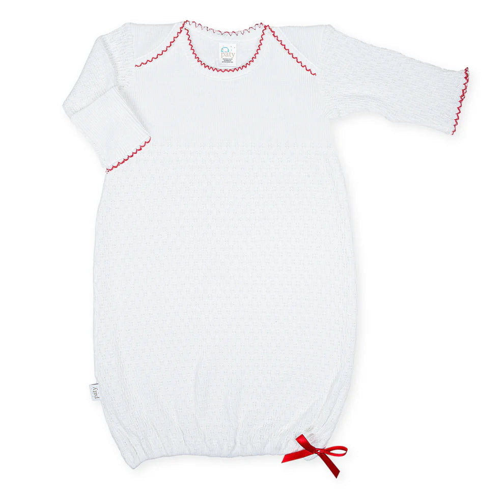White baby gown with red trim on a white background