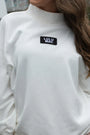 White turtleneck sweater with Lulu Mac logo worn by a person outdoors.