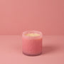 Pink candle in a glass container on a pink background